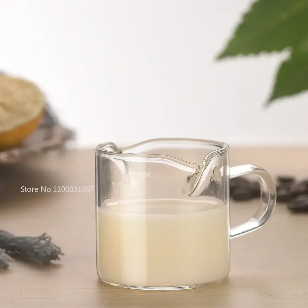 Clear glass cup measuring jug with wooden handle filled with creamy liquid perfect as a milk latte jug