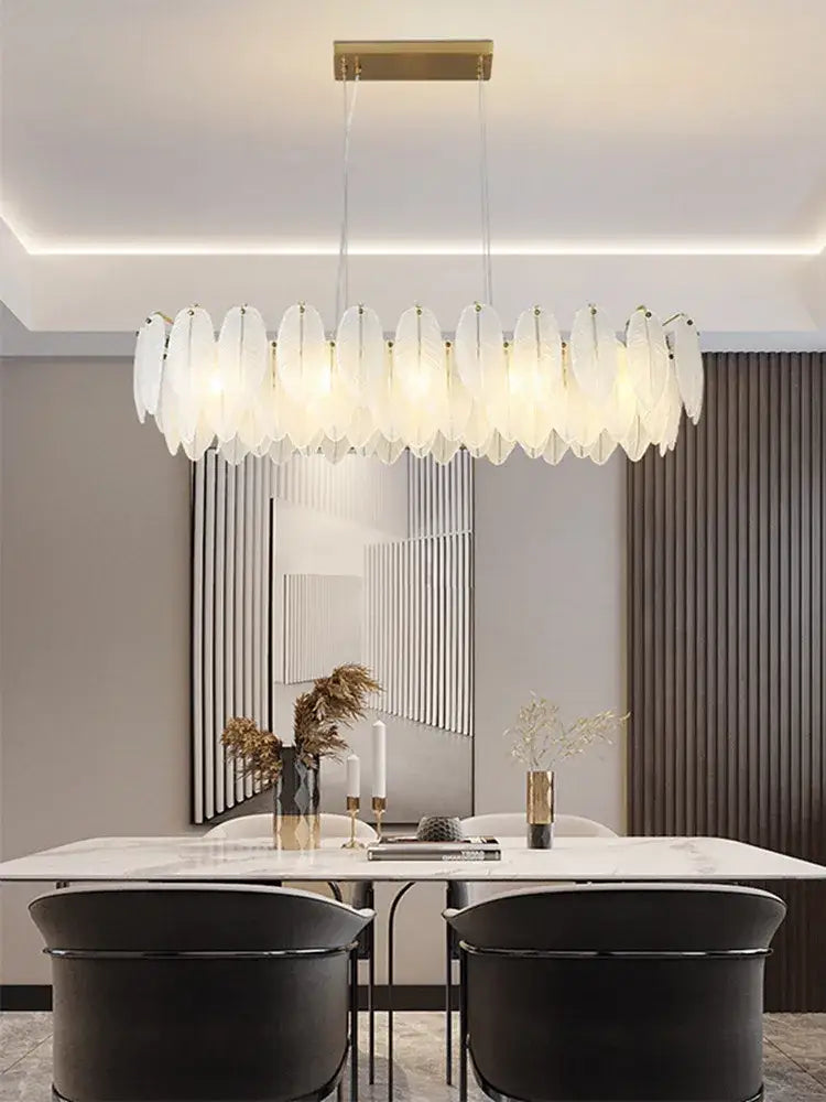 A modern elongated glass feather chandelier with translucent white shades and a gold-toned brass ceiling mount