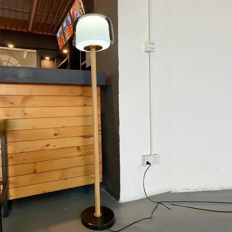 Modern glass floor lamp with a sleek white glass shade and slender bamboo pole base for living room use