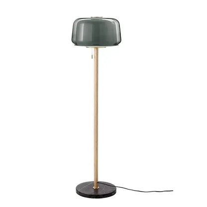 Modern glass floor lamp with a dark green smoked glass shade, wood pole, and black marble base for living room use
