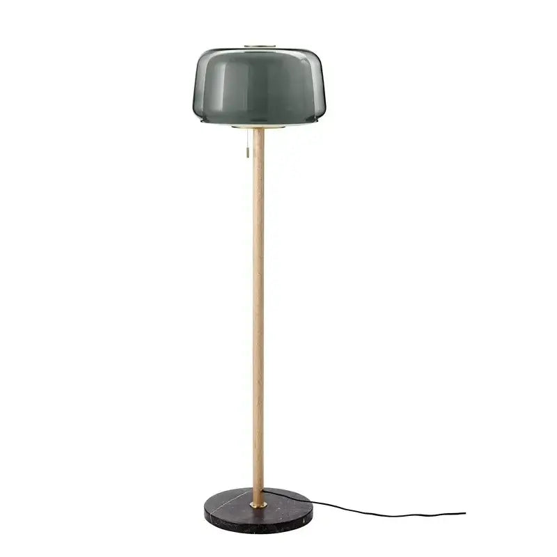 Modern glass floor lamp with a dark green smoked glass shade, wood pole, and black marble base for living room use