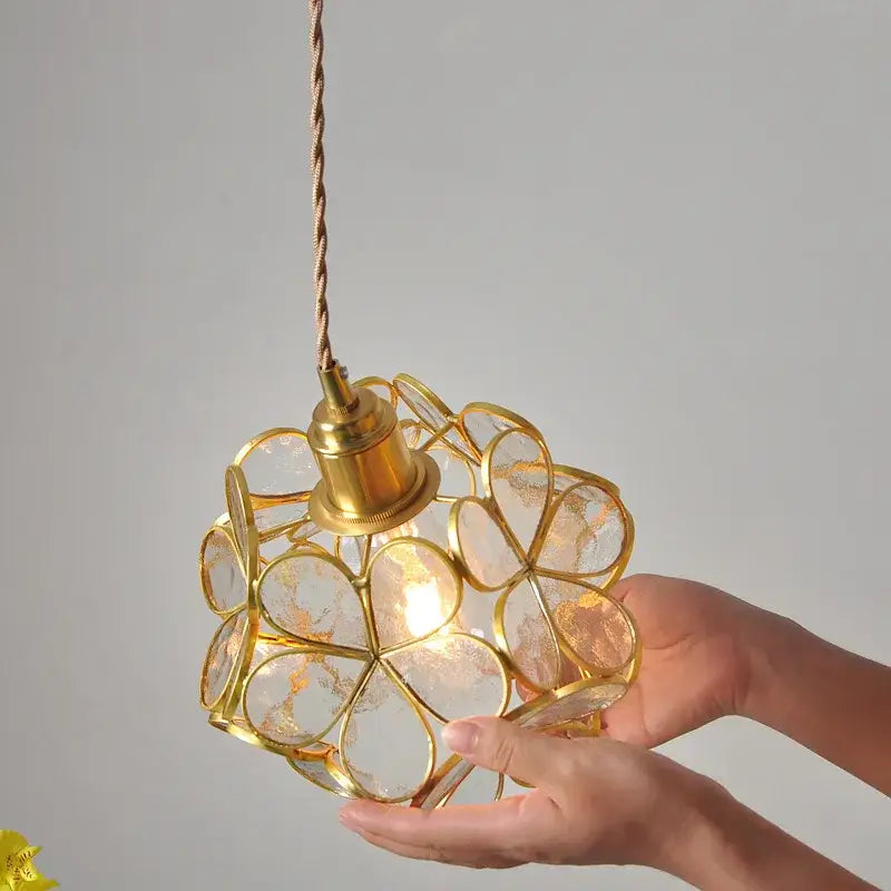 A delicate gold-toned modern glass flower led pendant light with spherical clear flower-shaped panels for dining room