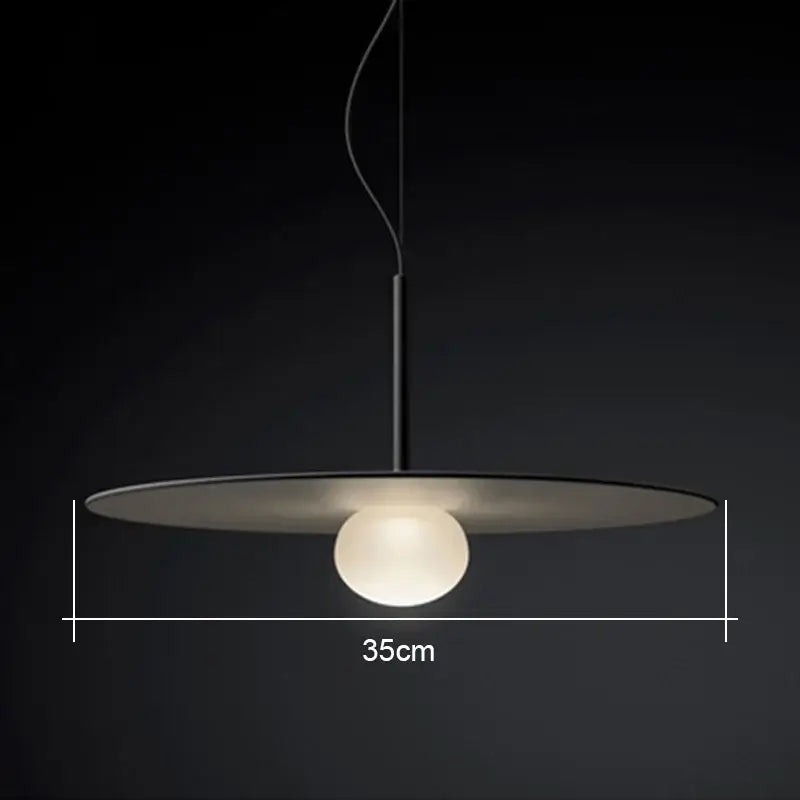 Minimalist black pendant light with a sleek glass flying saucer shade and glowing frosted globe for living room use