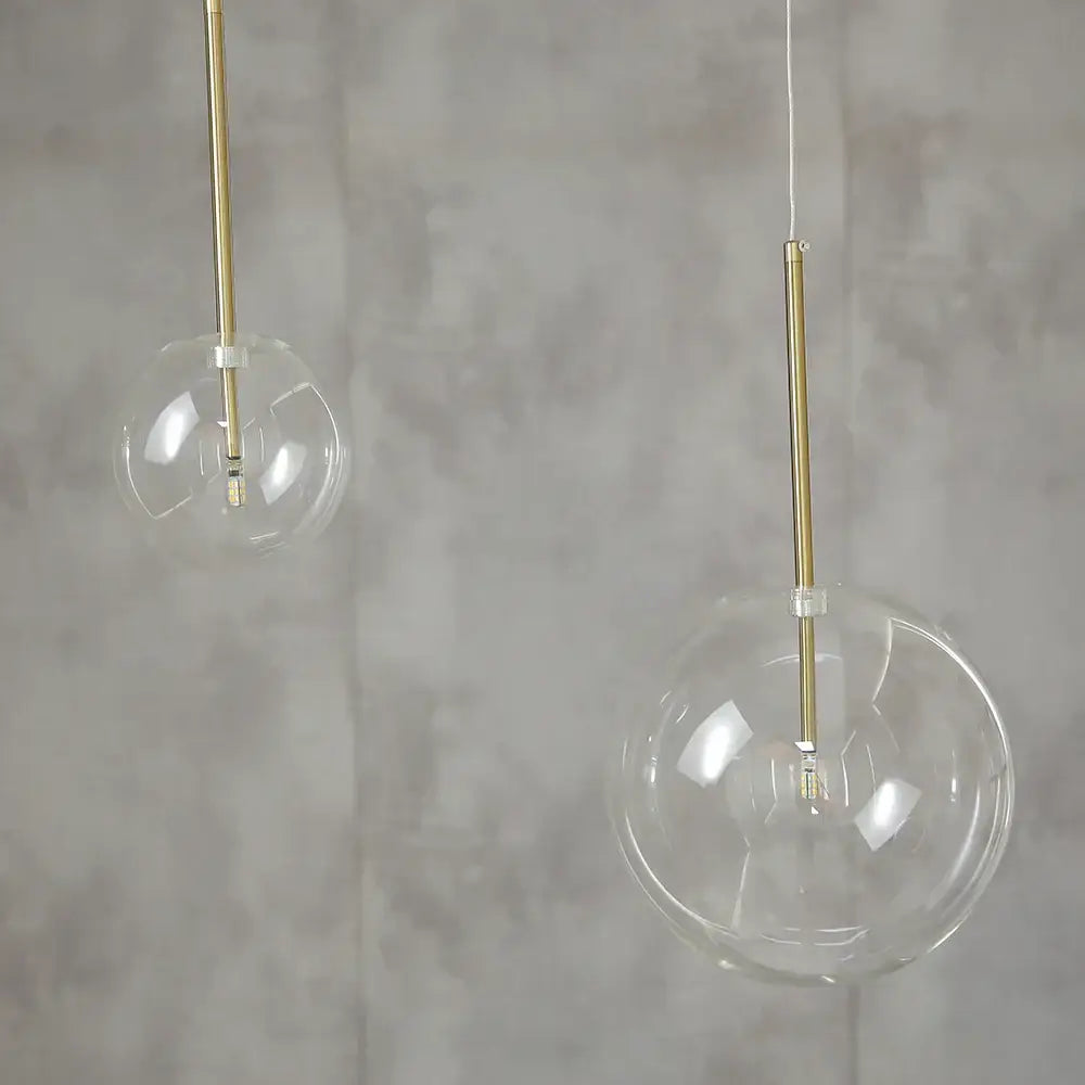 Modern glass globe chrome pendant light featuring clear glass globe pendant lights with slender gold-toned rods