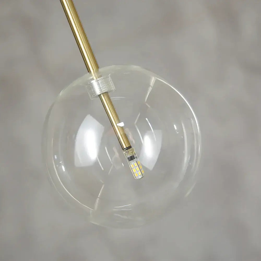 Modern glass globe chrome pendant light featuring a clear glass globe with brass rod and led bulb for dining room use