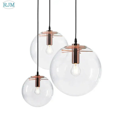 Set of three clear glass globe chrome pendant light fixtures with copper-toned metal for modern dining room lighting