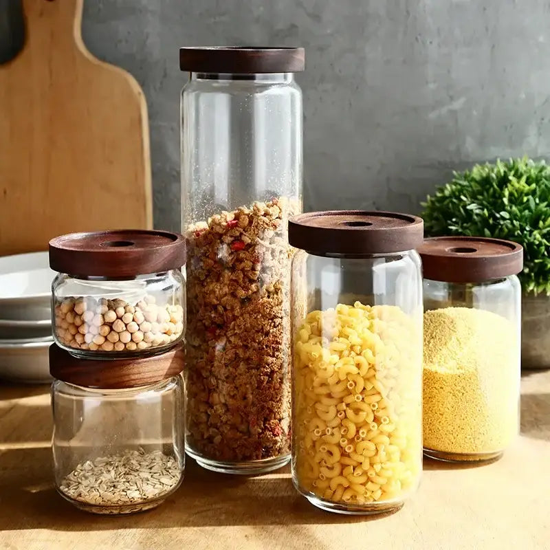 Set of clear glass hermetic storage jars with dark wood airtight lids filled with dry goods by decorbites glass hermetic