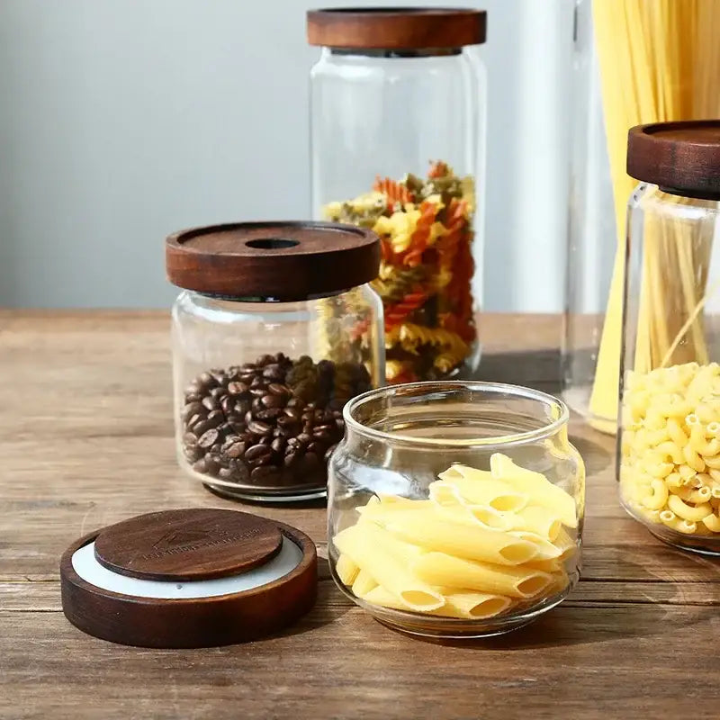 Clear glass hermetic storage jar with dark wood airtight lid filled with yellow penne pasta by decorbites glass hermetic