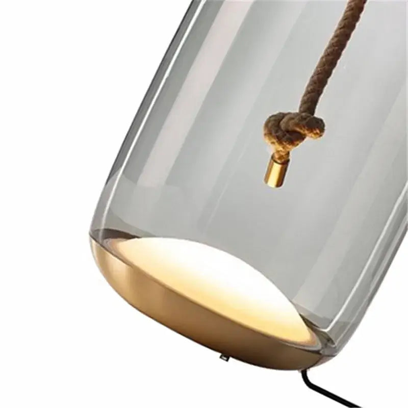 Modern glass knot table lamp with translucent gray glass shade brass base and hanging rope detail for bedroom decorbites brokis knot
