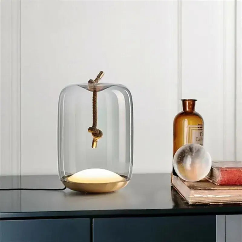 Modern glass knot table lamp with transparent glass cover and gold metal pendant on a brass decorbites brokis knot base
