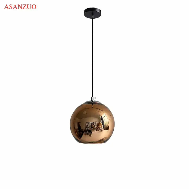A sleek spherical copper-finished glass pendant light with reflective globe and black cord for modern kitchens