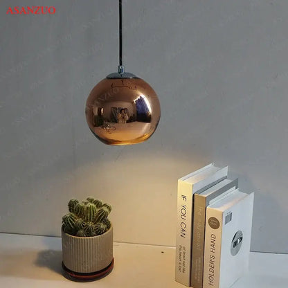 Copper-finished spherical glass pendant lights with reflective metallic surface and chrome fixture for inviting atmosphere