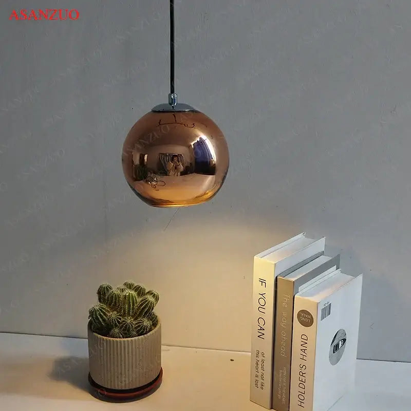 Copper-finished spherical glass pendant lights with reflective metallic surface and chrome fixture for inviting atmosphere