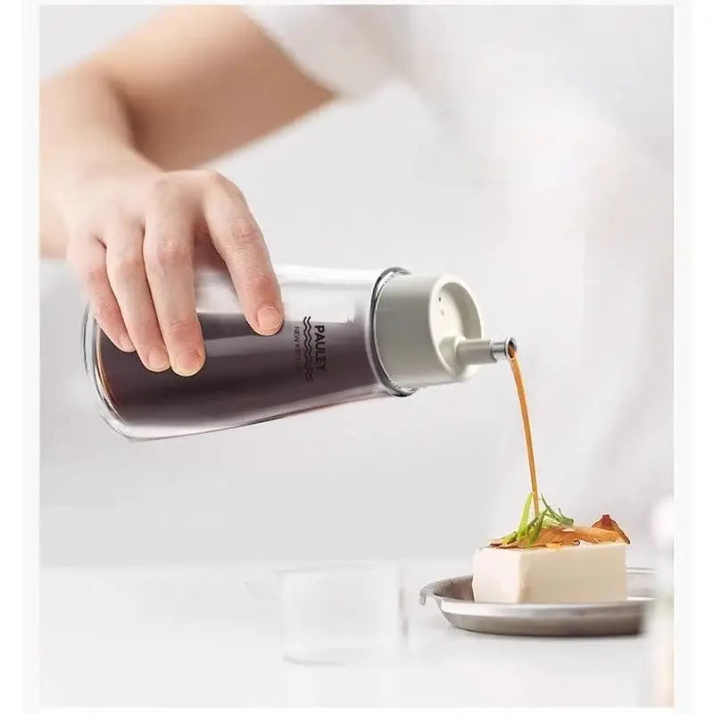 Clear glass seasoning bottle with gray metal cap and pump nozzle branded pauli in modern glass seasoning bottle set