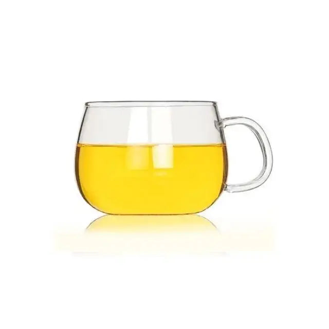 Modern glass tea cup with handle filled halfway with golden-yellow liquid for kitchen drinkware use