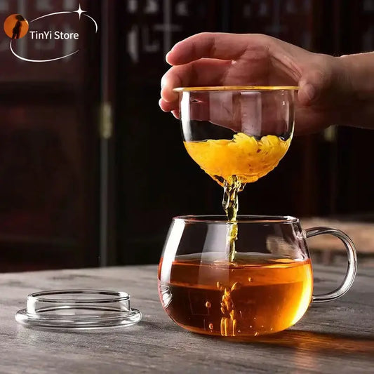 Modern clear glass tea cup with handle filled with amber-colored glass tea for kitchen drinkware use