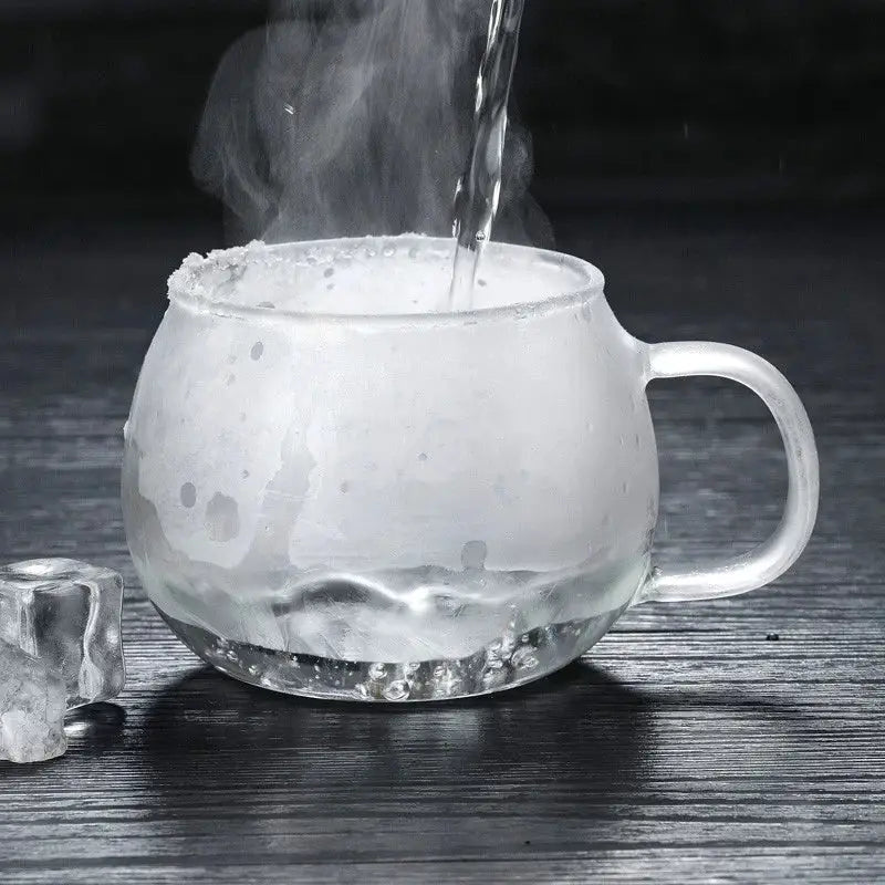 Modern clear glass tea cup with rounded body filled with steaming hot water for kitchen drinkware use