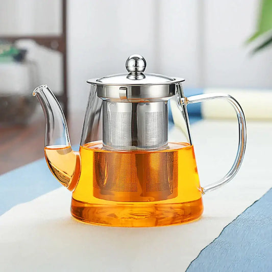 Modern glass tea infuser pot with stainless steel lid and built-in filter holding golden yellow tea