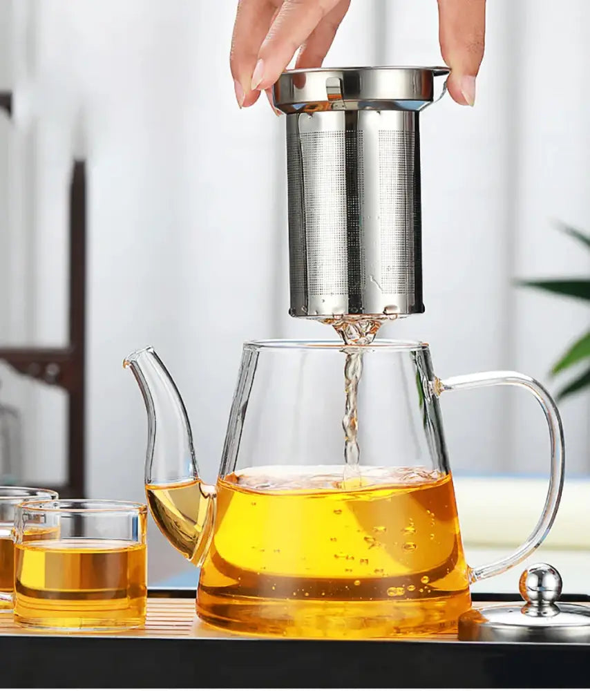 Modern clear glass tea infuser pot with stainless steel infuser filled with golden tea for filtered brewing