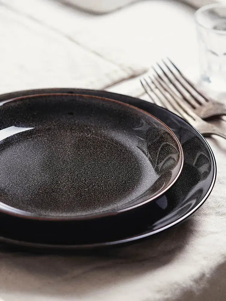 Black ceramic round plate with speckled glaze and subtle rim detailing from decorbites ceramic round collection