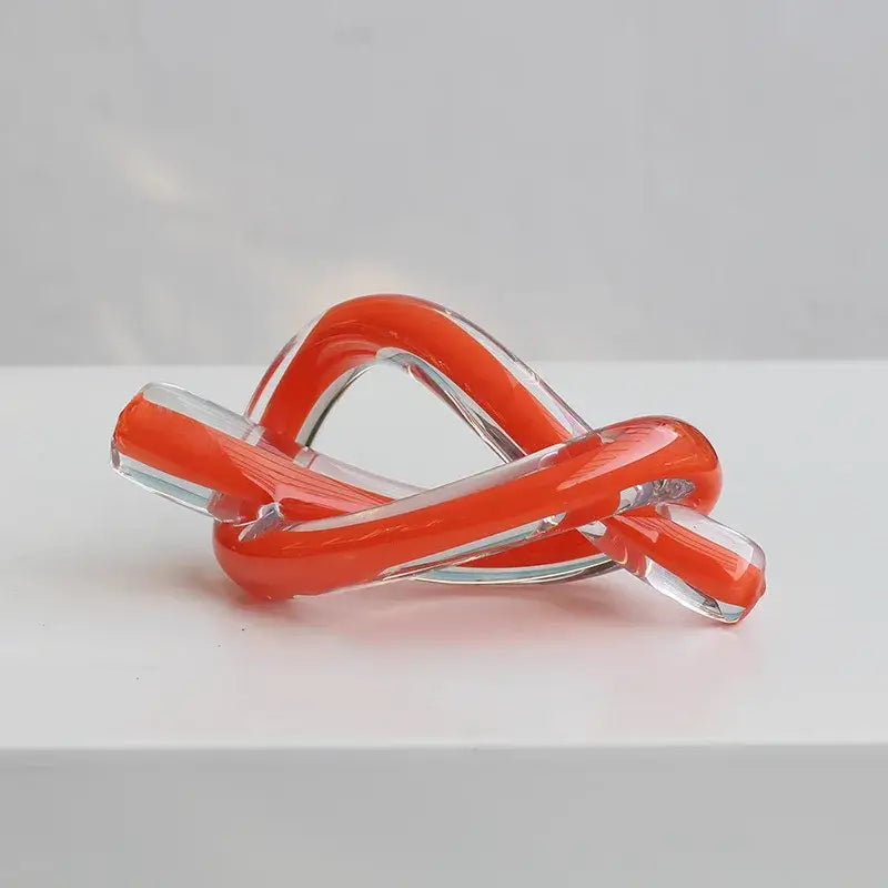 Modern glossy black geometric glass sculpture featuring a vibrant orange and clear glass sculpture with a twisted knot design decorbites geometric glass