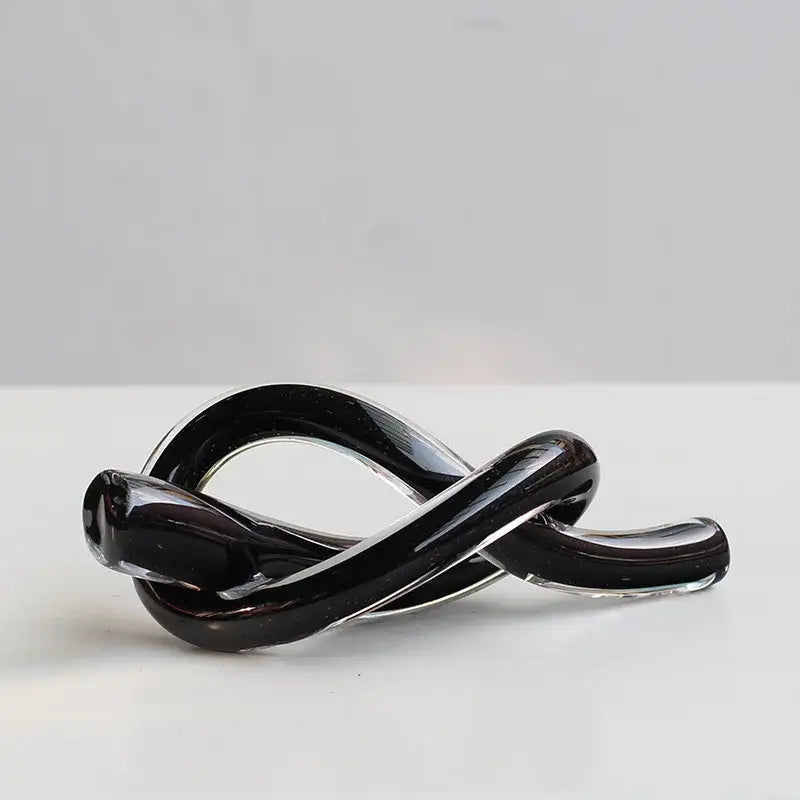 A sleek glossy black geometric glass sculpture with a smooth intertwined knot design for modern decorbites decor