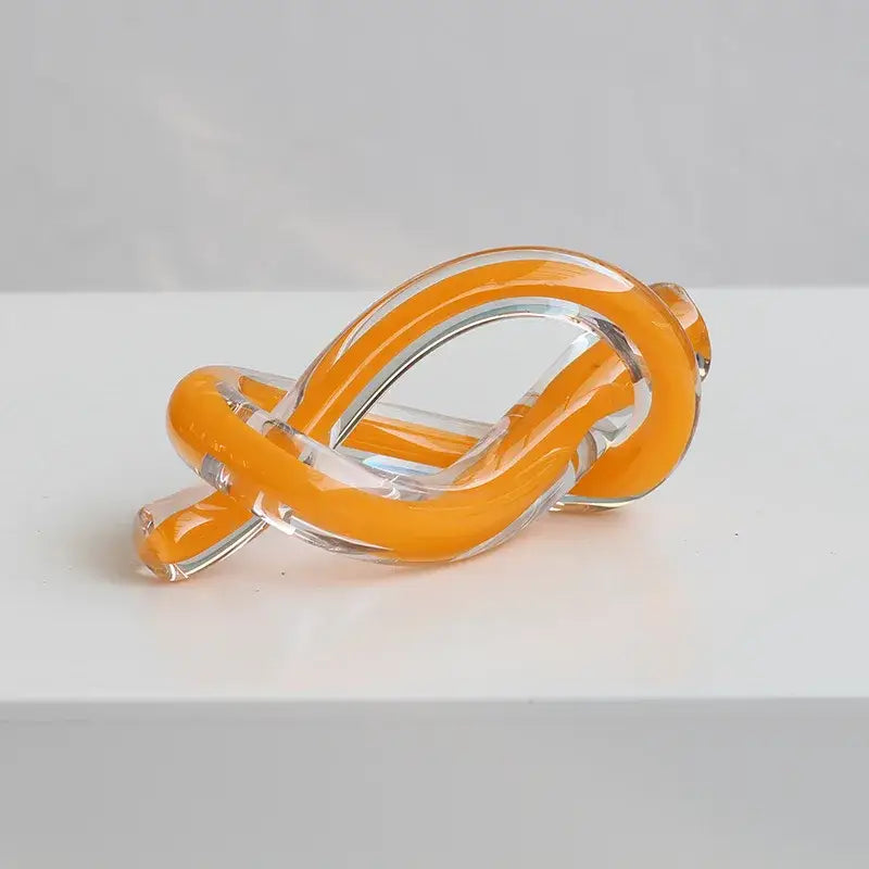 Modern translucent orange and clear glass sculpture knot decor featuring geometric glass sculpture twine design by decorbites