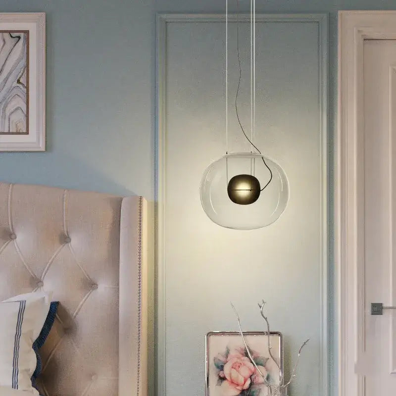 A modern glossy black glass ball pendant light with clear globe and brushed brass bulb for dining room decorbites brokis big