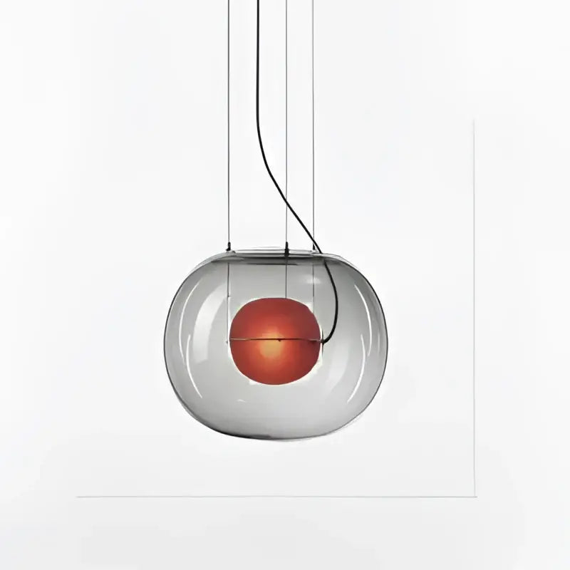 A modern glossy black glass ball pendant light with a glowing orange bulb by decorbites brokis big for dining room decor
