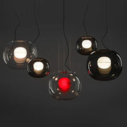 Modern glossy black glass ball pendant light with warm white or red illuminated interiors for dining room decorbites brokis big