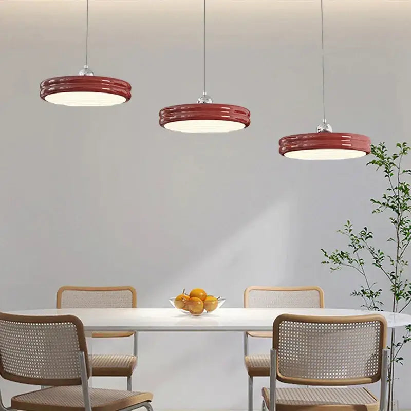 Three modern red ribbed pendant lights hang above the dining table complementing decorbites circular dimmable pendant light decor