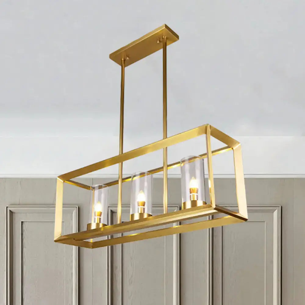 Gold-finished rectangular pendant light with three clear glass cylinders illuminated for dining room use
