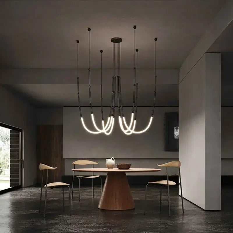 Modern black metal pendant light with curved glowing white acrylic tubes and brushed nickel accents for dining rooms
