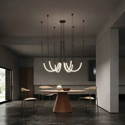 Modern black metal pendant light with curved glowing white acrylic tubes and brushed nickel accents for dining rooms