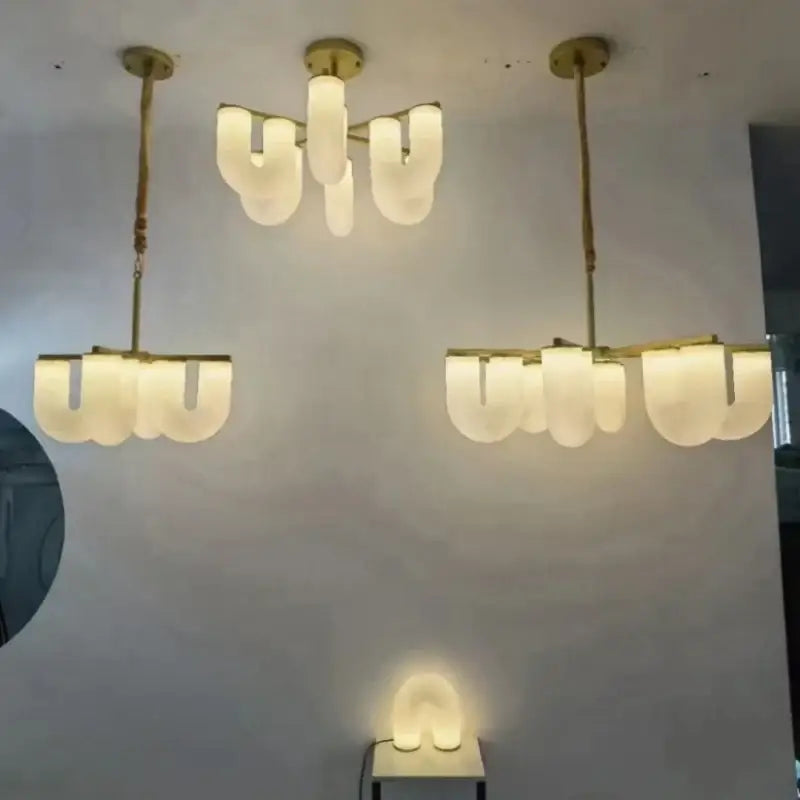 Modern gold acrylic pendant lights featuring a gold metal chandelier with frosted glass u-shaped shades for dining room