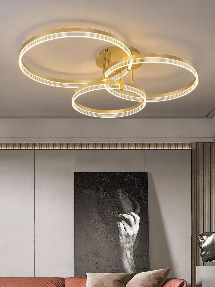 Modern gold acrylic round ring ceiling light with three interlocking rings emitting warm glow for living room decorbites acrylic round