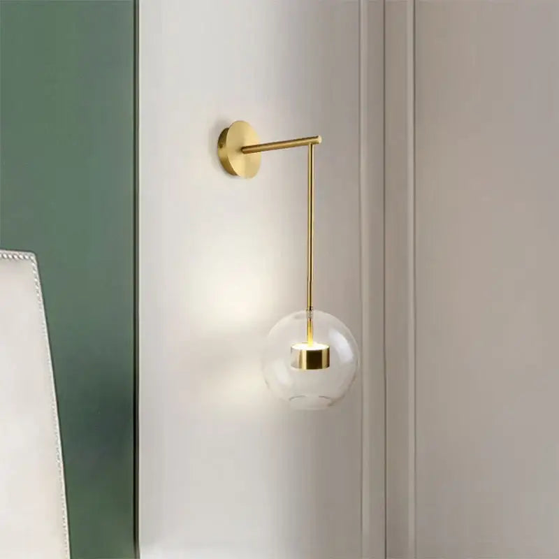 Modern gold adjustable direction wall lamp with a gold-toned minimalist arm and clear glass globe for bedroom decorbites wall light