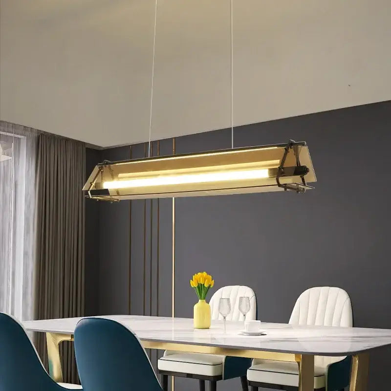 Modern gold amber led pendant lamp with a sleek rectangular design hanging above dining table decorbites amber led