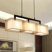 Modern gold and beige fabric island light with three illuminated shades and black suspension lighting bar for kitchen use