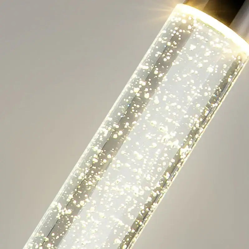 Modern gold and black decorbites crystal chandelier with clear cylindrical pendant, glowing bubbles, and warm white led illumination