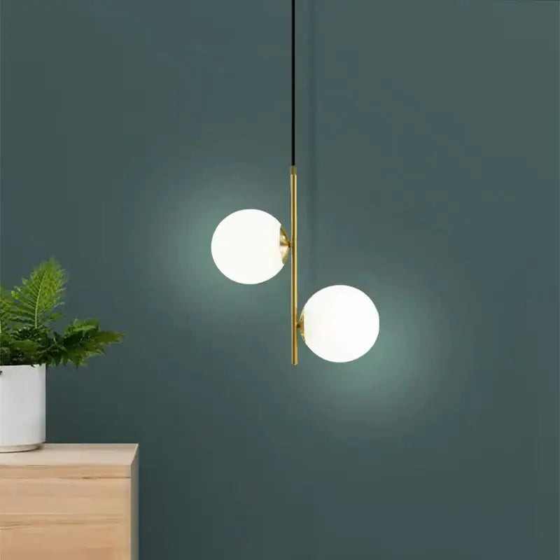 Modern gold and black glass ball led pendant light with two glowing white spherical shades and slender metal rod suspension