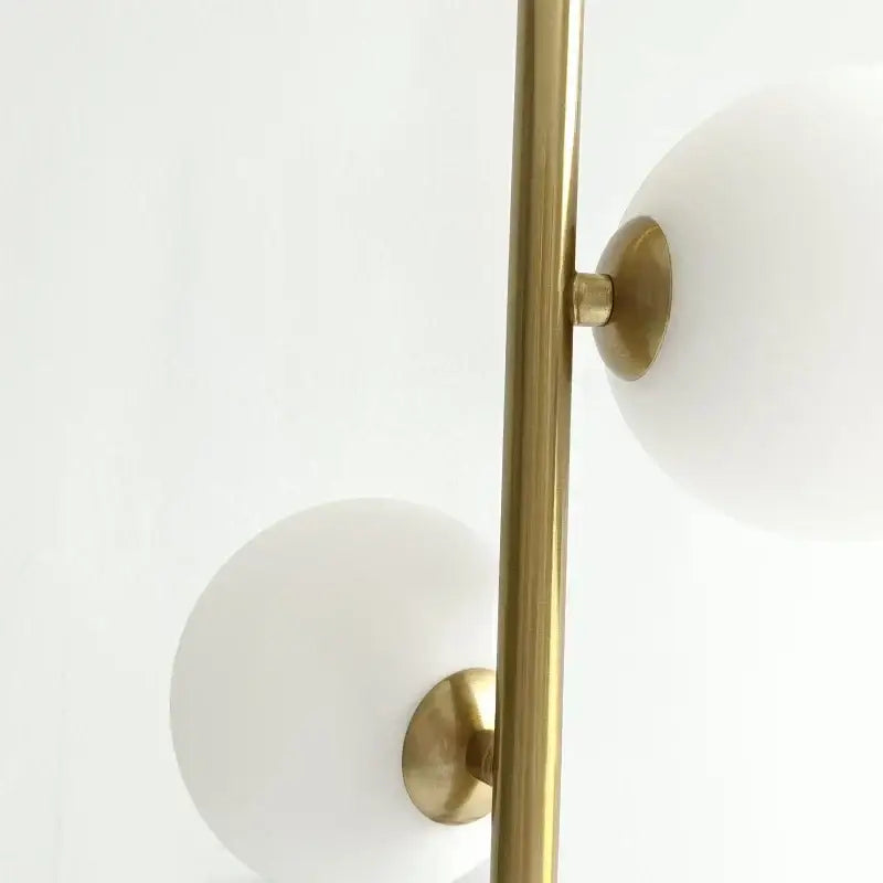 Modern brass-finished floor lamp with frosted white glass ball led shades complementing gold and black pendant lights