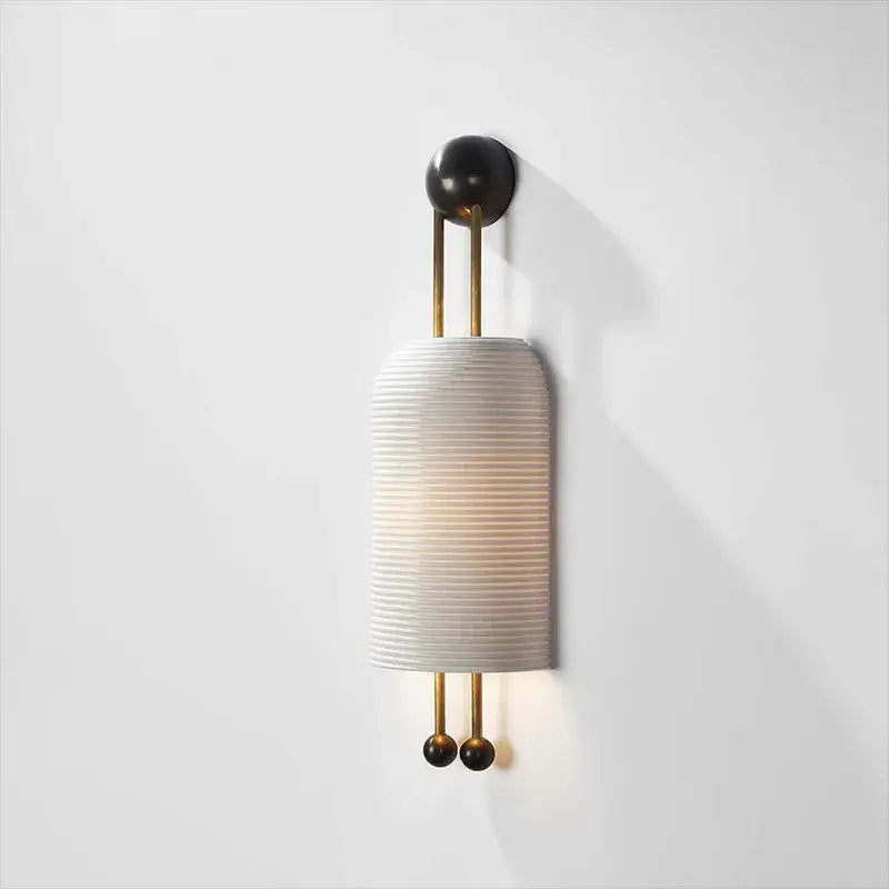 A modern wall sconce with a ribbed off-white shade and brass accents complements a glass led chandelier design