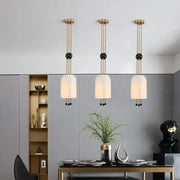 Three modern gold and black glass led chandelier pendant lights with frosted shades hang above a dining table