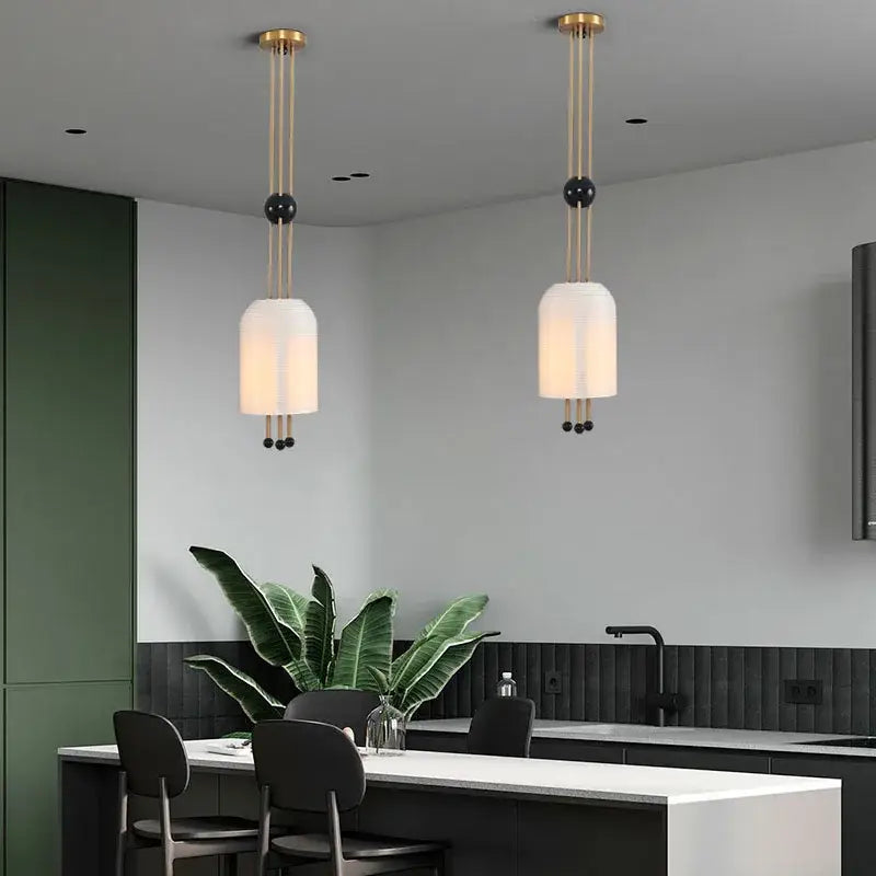 Modern gold and black glass led chandelier with metal rods and glass led shades hanging above kitchen island