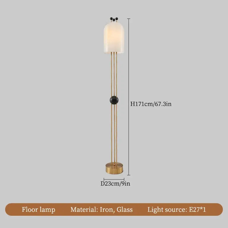A tall slender floor lamp with brass metal frame and off-white glass shade complementing a modern glass led chandelier