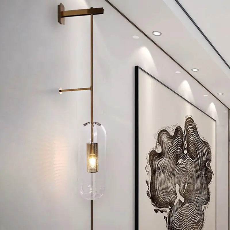 Modern gold and black orb wall lamp featuring a brass sconce with clear glass pendant for living rooms