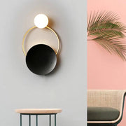 Modern gold and black orb wall lamp featuring a minimalist gold frame and illuminated white orb for living rooms