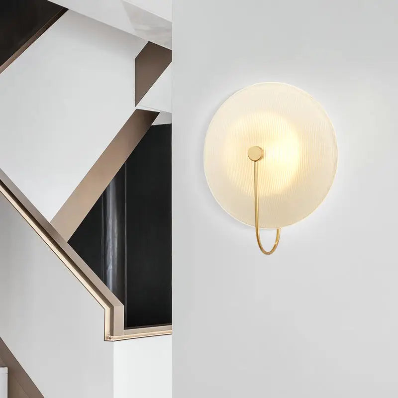 Minimalist wall lamp with frosted glass disc and gold-toned metal frame for modern living rooms