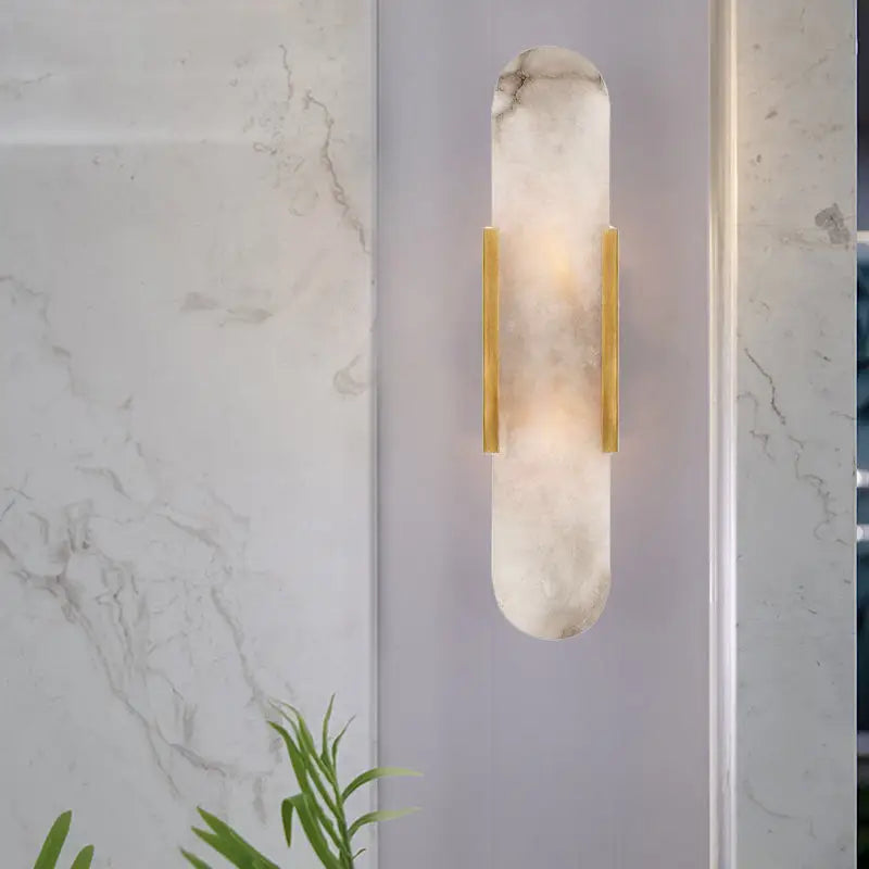 A sleek modern wall lamp with a translucent white marble body and gold metal accents for living rooms